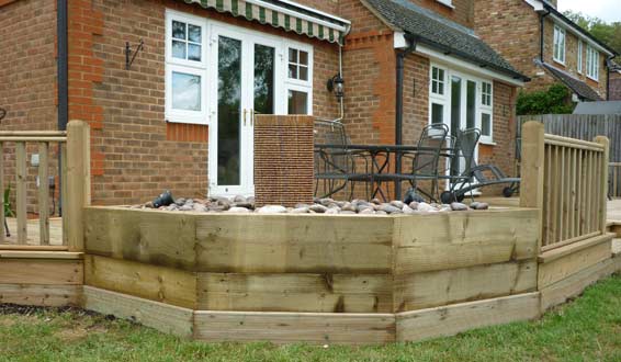 Stone water feature in raised sleeper edged bed